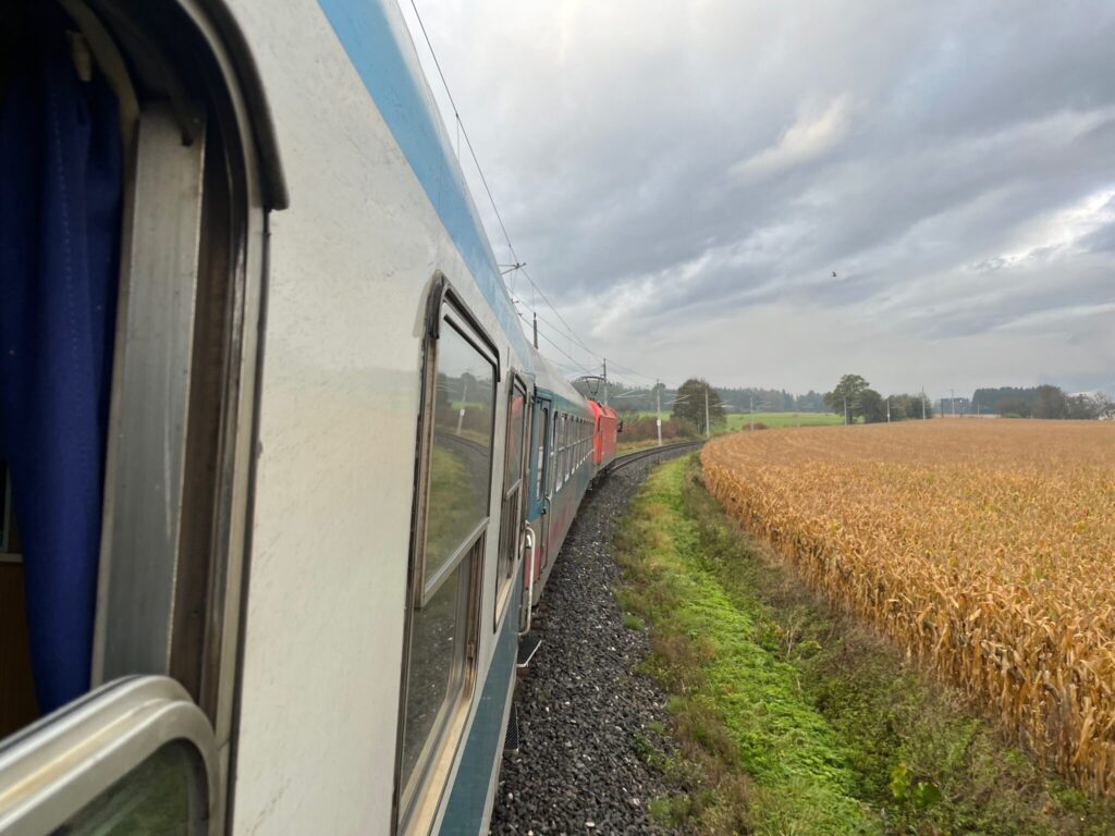 Train to the left, can see side of locomotive in the middle, maize field to the right