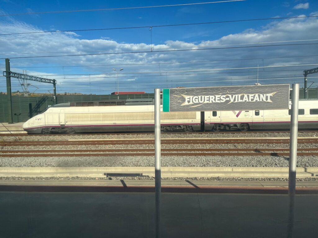 Renfe Series 100 AVE behind a sign saying Figueres Vilafant